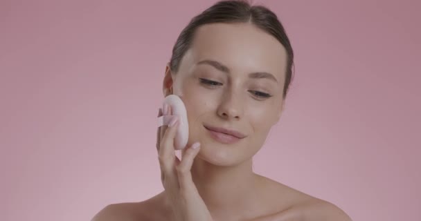 Молодая брюнетка с мягкой губкой для нанесения порошка на лицо — стоковое видео