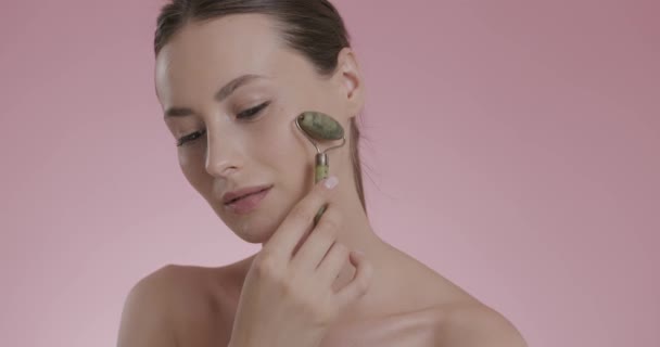 Portrait of beautiful woman using stone facial roller — Stock Video