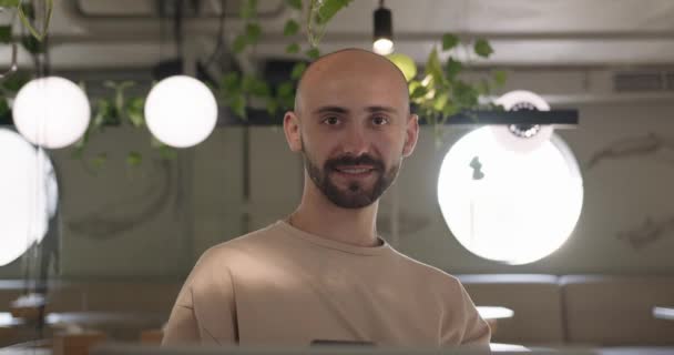 Portrait d'homme barbu souriant utilisant mobile au café — Video