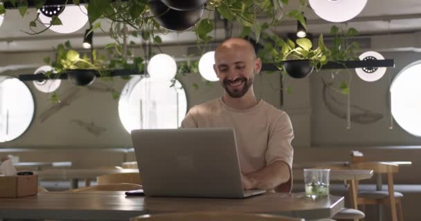 Sorrindo cara trabalhando no laptop no café acolhedor — Vídeo de Stock