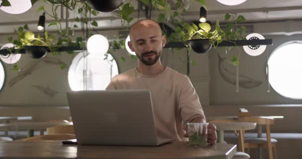 Snygg man som jobbar med trådlös bärbar dator på caféet — Stockvideo