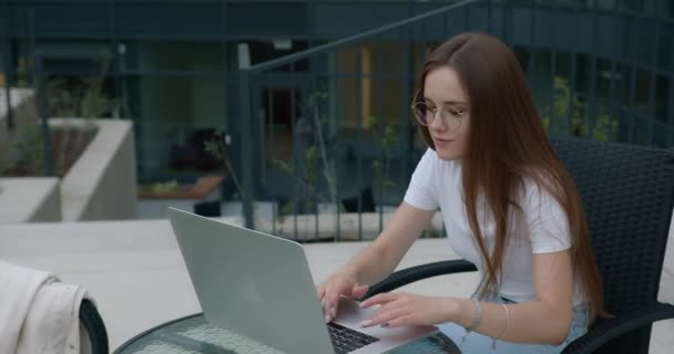 Mujer bonita escribiendo en el ordenador portátil mientras estudia al aire libre — Vídeos de Stock