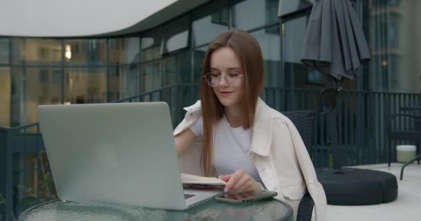 Trevlig kvinna som använder laptop för att studera utomhus — Stockvideo