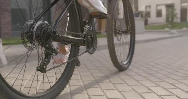 Primer plano de la mujer en zapatillas deportivas montar en bicicleta en la calle — Vídeo de stock