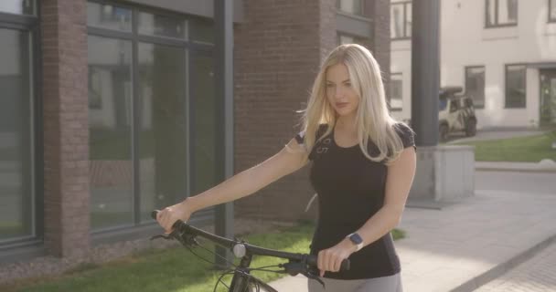 Mulher branca segurando bicicleta nas mãos e andando na rua — Vídeo de Stock