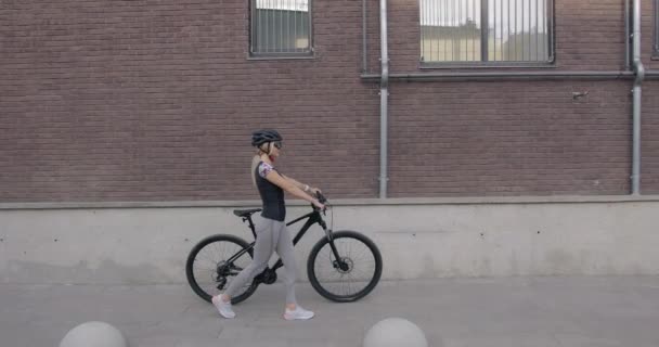 Mujer atlética en ropa deportiva caminando con bicicleta en la calle — Vídeo de stock
