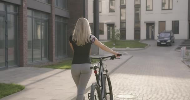 Rückansicht einer Frau, die mit schwarzem Fahrrad im Freien unterwegs ist — Stockvideo
