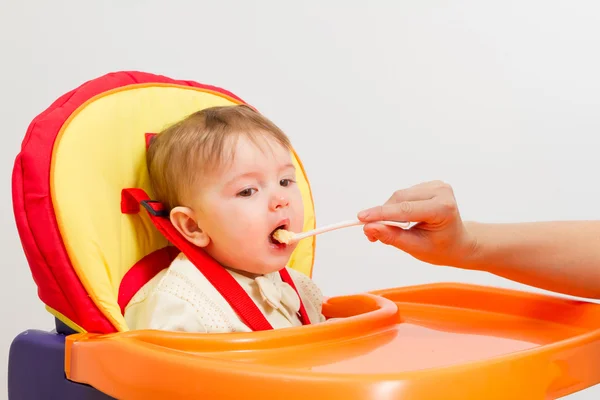 Babyjongen eten met lepel thuis — Stockfoto