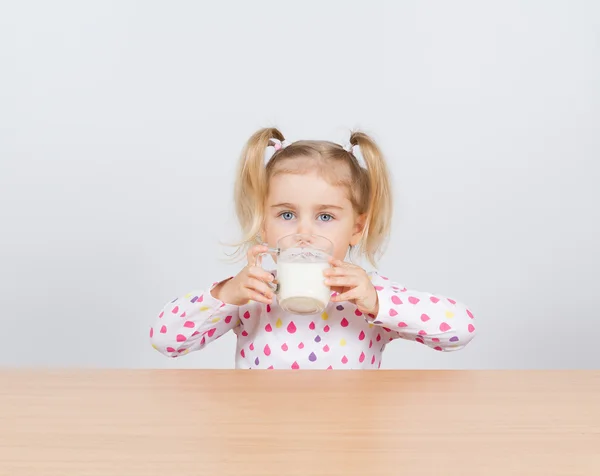 Glückliches kleines Mädchen mit einem Glas Milch. — Stockfoto