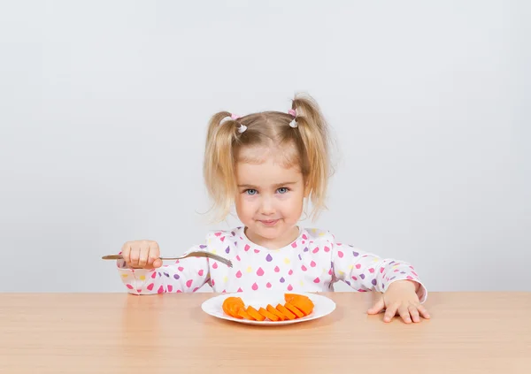 Meisje eet wortel met vork. — Stockfoto