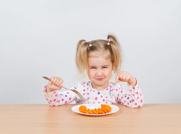 Meisje eet wortel met vork. — Stockfoto