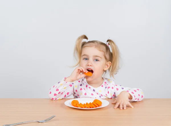 Meisje eet wortel met vork. — Stockfoto