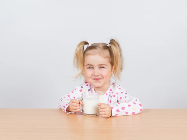 Glückliches kleines Mädchen mit einem Glas Milch. — Stockfoto