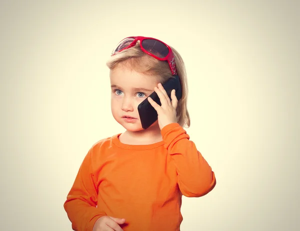 चश्मे में छोटी लड़की स्मार्टफ़ोन पर बात कर रही है  . — स्टॉक फ़ोटो, इमेज