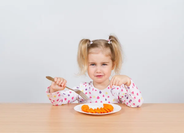 Meisje eet wortel met vork. — Stockfoto