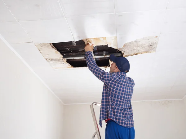 Mann repariert eingestürzte Decke. — Stockfoto