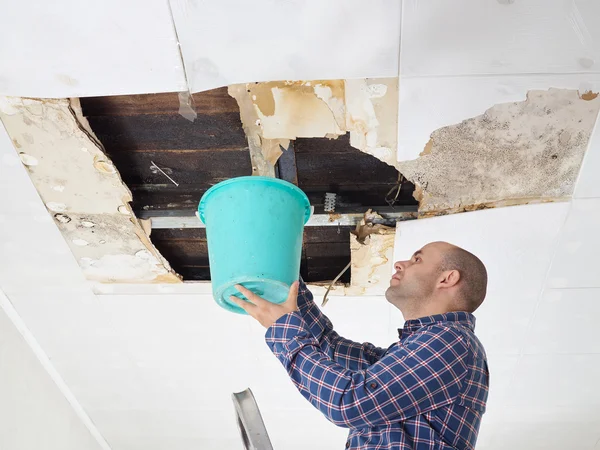 Man verzamelen van Water In de emmer aan plafond — Stockfoto