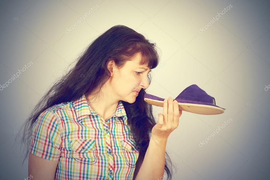 Young woman sniffs smelly Slippers. — Stock Photo © volkovslava 105092352