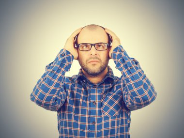 Başını elleri ile tutarak gözlüklü adam.