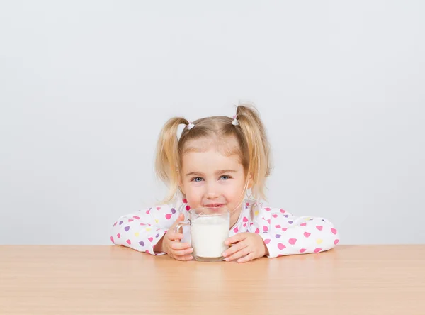 Glückliches kleines Mädchen mit einem Glas Milch. — Stockfoto