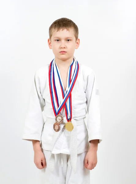 Karate pojke i vit kimono med medaljer kämpar — Stockfoto