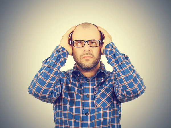 Başını elleri ile tutarak gözlüklü adam.