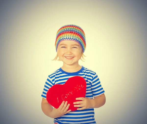 Niña sosteniendo un juguete rojo del corazón . — Foto de Stock