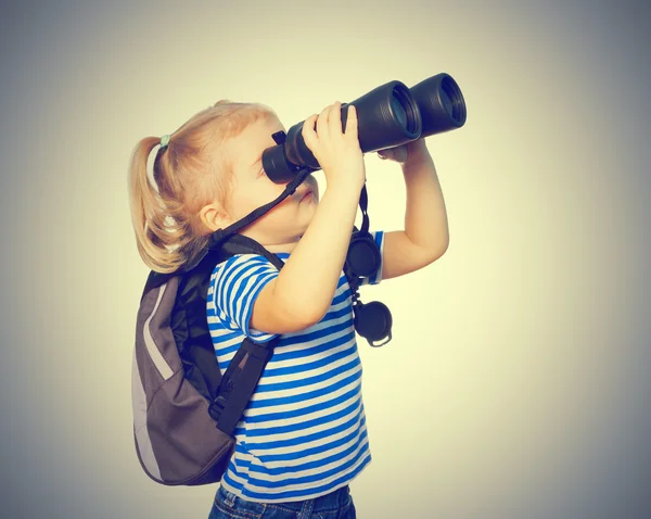 Kleines lustiges Mädchen schaut durch Ferngläser. — Stockfoto