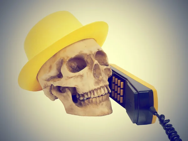 Skull in yellow hat on phone — Stock Photo, Image