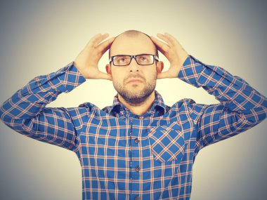 Başını elleri ile tutarak gözlüklü adam.