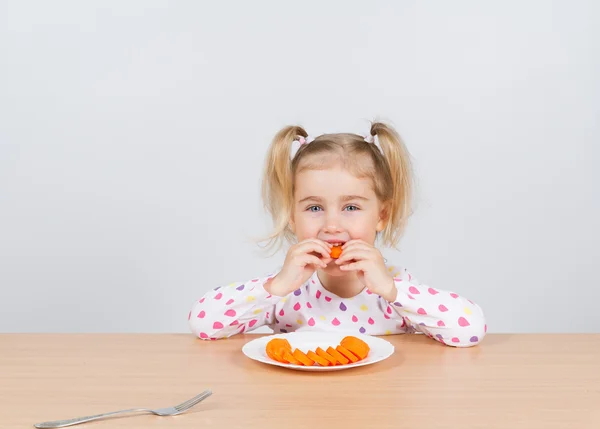 Meisje eet wortel met vork. — Stockfoto