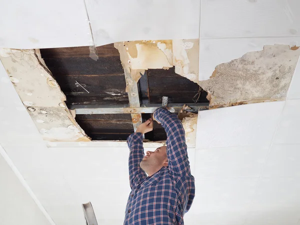 Homem reparação teto desmoronado . — Fotografia de Stock