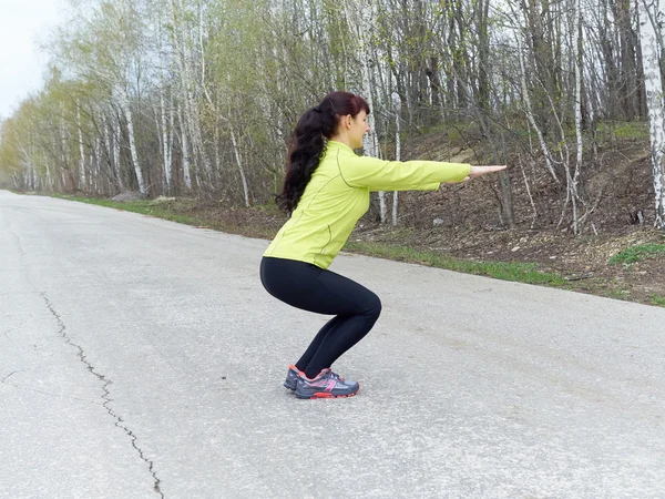 Jonge vrouw squat buiten in de natuur — Stockfoto