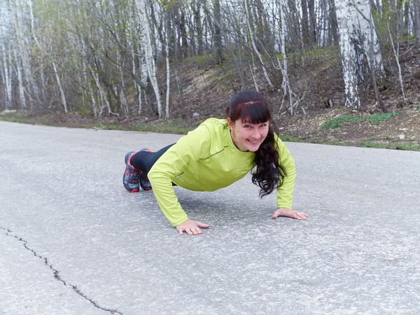 Jonge vrouw pushups buiten in de natuur. — Stockfoto