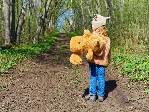Dziecko jest chodzenie w dół ścieżki z misiem — Zdjęcie stockowe