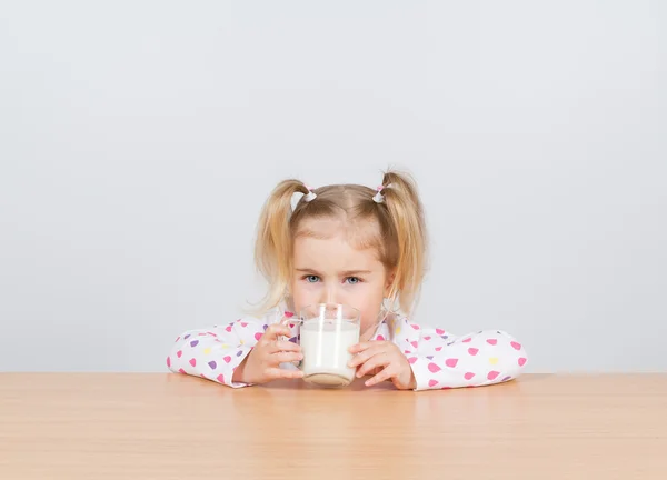 Glückliches kleines Mädchen mit einem Glas Milch. — Stockfoto