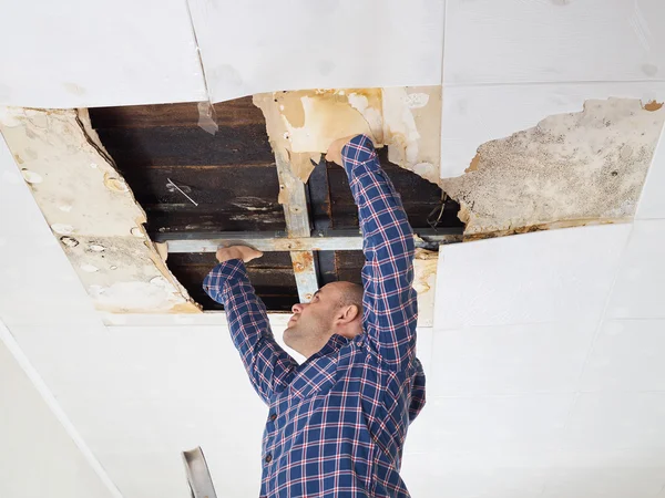 Человек ремонтирует рухнувший потолок . — стоковое фото