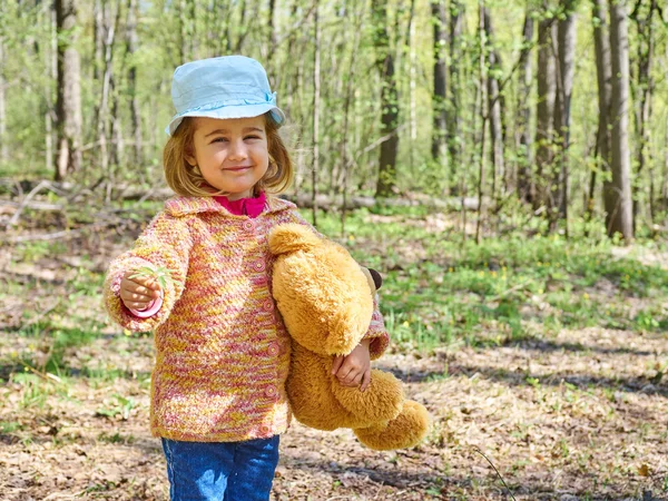 Meisje met teddybeer geeft gele bloem. — Stockfoto