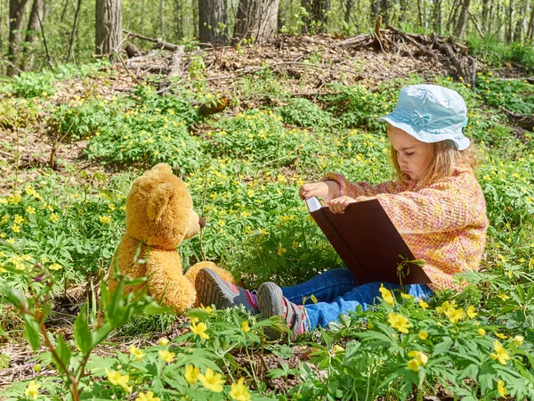 Niedliches Mädchen liest Buch Teddybär — Stockfoto