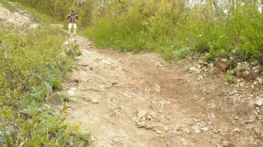 Sırt çantalı bir adam orman yolunda yokuş aşağı yürüyor. .