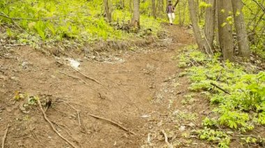 Sırt çantalı bir adam orman yolunda yokuş aşağı yürüyor. .