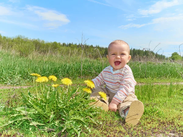 タンポポの花の黄色と緑の草原に座って赤ちゃん — ストック写真