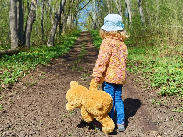 Niño está caminando por el camino con el oso de peluche — Foto de Stock