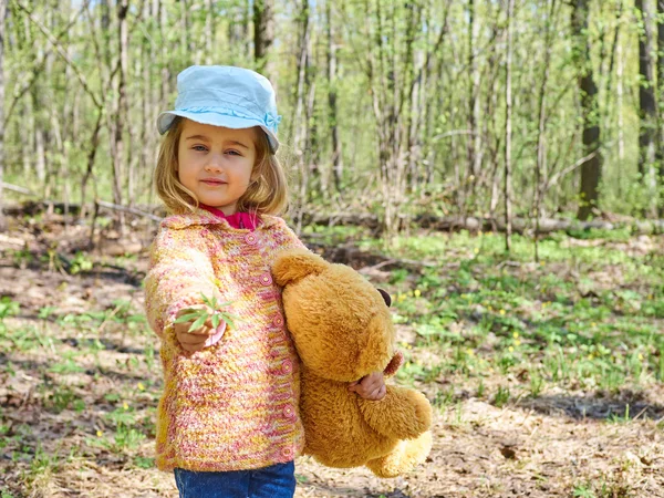 Mädchen mit Teddybär gibt gelbe Blume. — Stockfoto