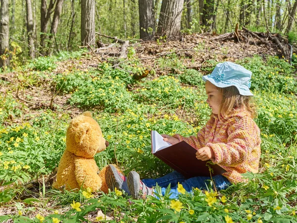 Niedliches Mädchen liest Buch Teddybär — Stockfoto