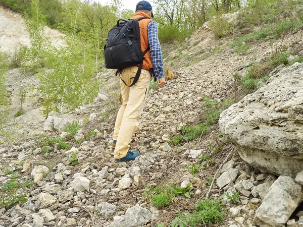 Homem com uma mochila caminhar subida a trilha da floresta  . — Fotografia de Stock