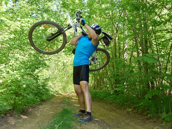 Ciclista homem carrega bicicleta na floresta verde no verão . — Fotografia de Stock
