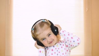 küçük kız kulaklıklar müzik dinlemek. ev, teknoloji ve müzik