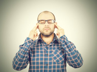 Başını elleri ile tutarak gözlüklü adam.