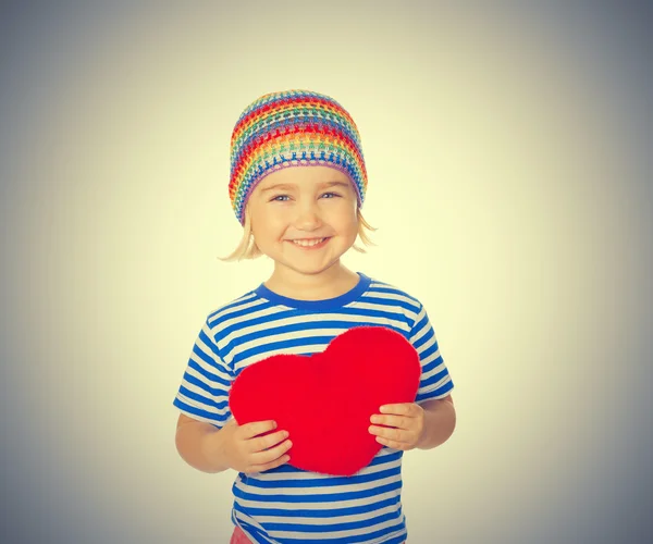 Niña sosteniendo un juguete rojo del corazón . — Foto de Stock